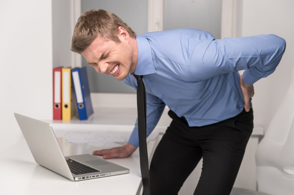 handsome man feeling pain in back. Businessman suffering from back pain at office