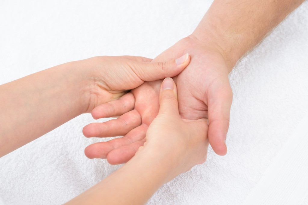 Close-up Of A Physiotherapist Massaging Palm Of A Man