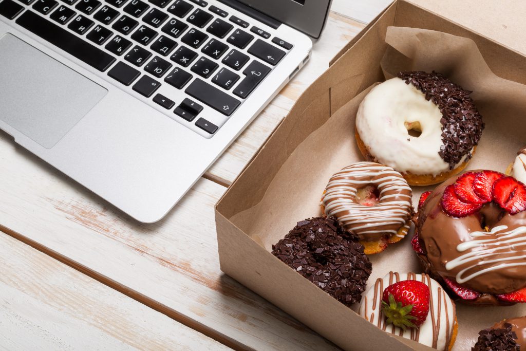 Ein Karton mit Donuts neben einer Tastatur