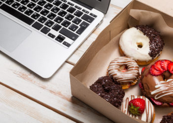 Ein Karton mit Donuts neben einer Tastatur