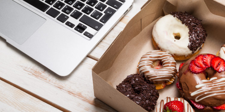 Ein Karton mit Donuts neben einer Tastatur