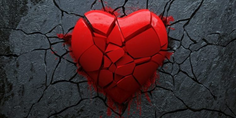 Ein kleine Teile zersprungenes rotes Herz auf schwarzem Hintergrund.