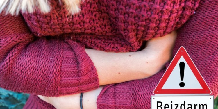 Eine Frau mit Bauchschmerzen hält sich die Arme schützend vor den Bauch.
