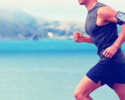 Mann mit Pulsmessgerät am Arm joggt am Meer