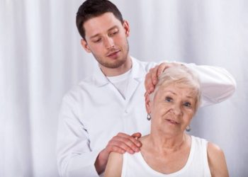 Therapeut behandelt Nackenbereich einer älteren Frau.
