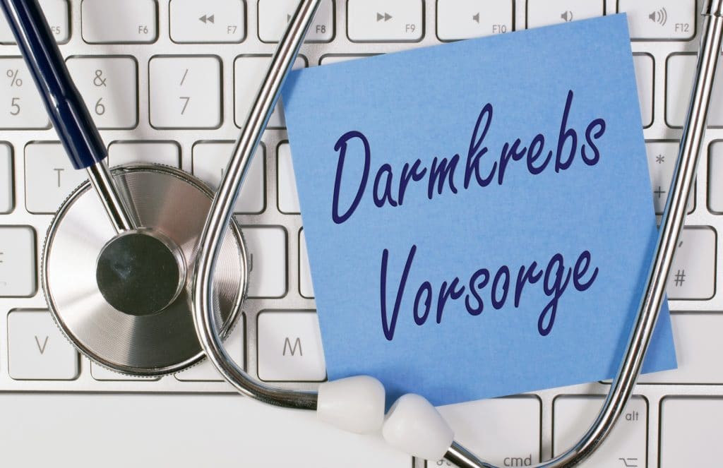 Tastatur, auf der ein Stethoskop und ein Zettel mit der Aufschrift Darmkrebs-Vorsorge liegt