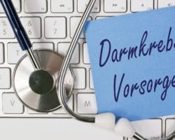 Tastatur, auf der ein Stethoskop und ein Zettel mit der Aufschrift Darmkrebs-Vorsorge liegt