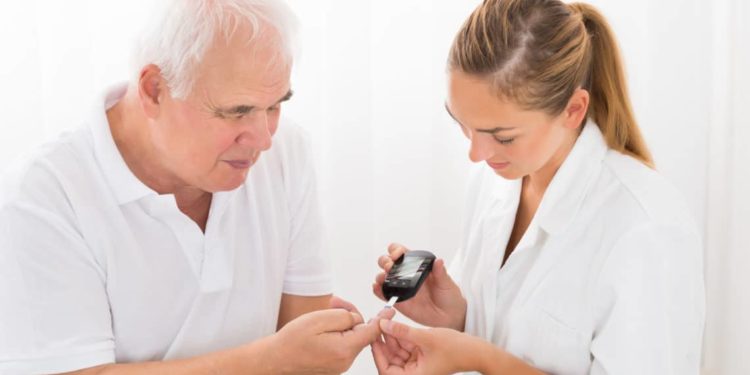 Medizinische Fachkraft führt bei älterem Patienten eine Blutzuckermessung durch