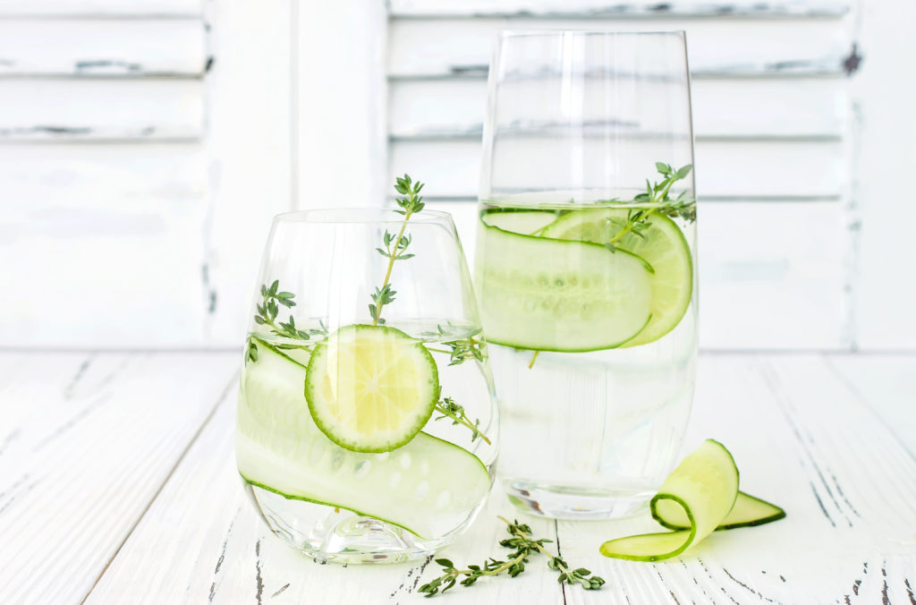 Zwei Gläser Wasser mit Limetten- und Gurkenscheiben