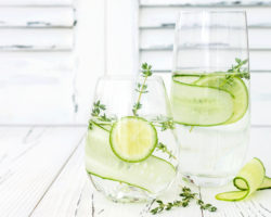 Zwei Gläser Wasser mit Limetten- und Gurkenscheiben