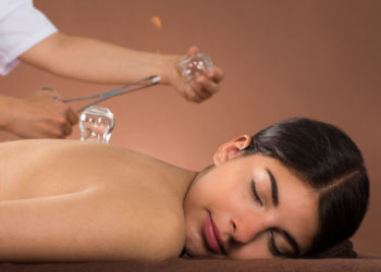 Close-up Of Person's Hand Holding Lit Camphor With Tong And Cup