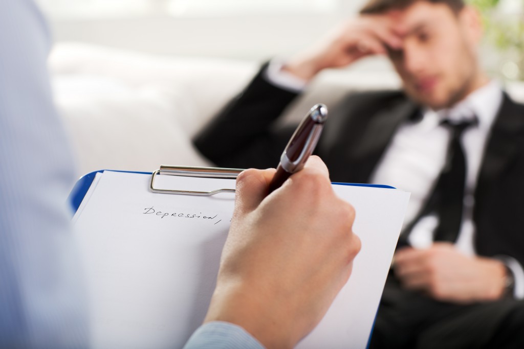 Over the shoulder view, of a business man sit on a couch talking to his psychiatrist