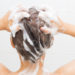 Woman washing her hair on white tiles background.