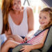 Mutter schnallt ihre Tochter im Auto-Kindersitz an