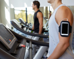 Zwei Männer laufen auf Laufbändern in einem Fitness-Studio.