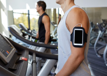 Zwei Männer laufen auf Laufbändern in einem Fitness-Studio.