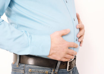 Ein Mann hält seine beiden Hände vor den Bauch.