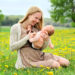 Junge Frau kitzelt ihr Baby auf einer Blumenwiese