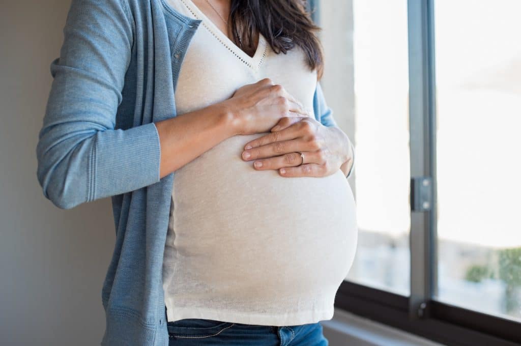 Schwangere Frau mit ihren Händen auf dem Bauch