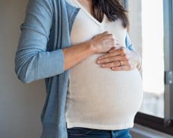 Schwangere Frau mit ihren Händen auf dem Bauch