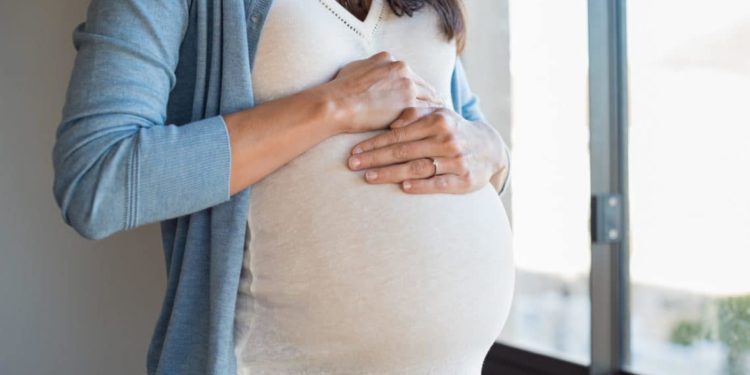 Schwangere Frau mit ihren Händen auf dem Bauch