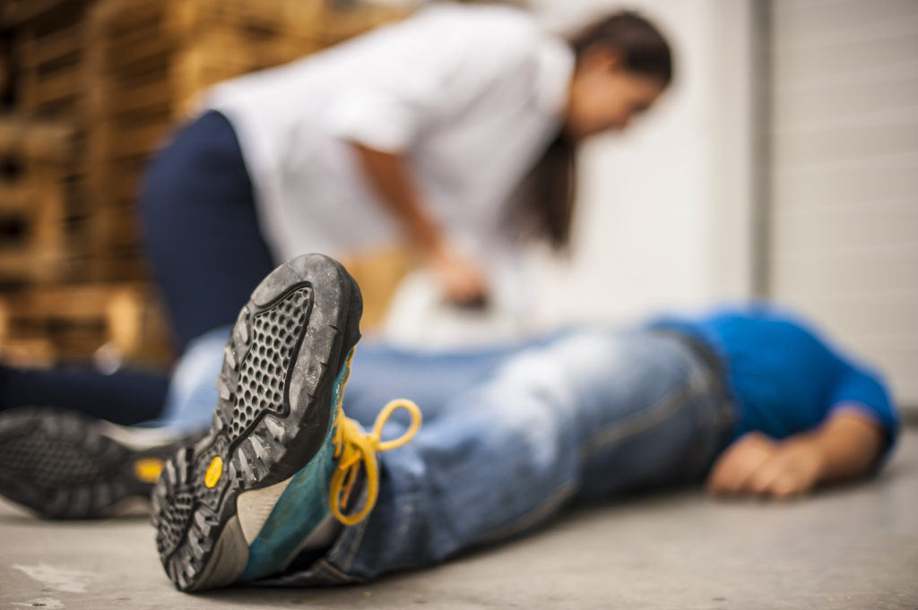 Frau beugt sich über einen am Boden liegenden Mann