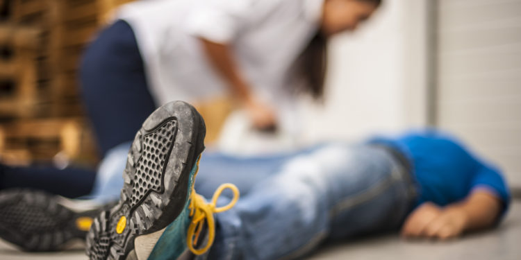 Frau beugt sich über einen am Boden liegenden Mann