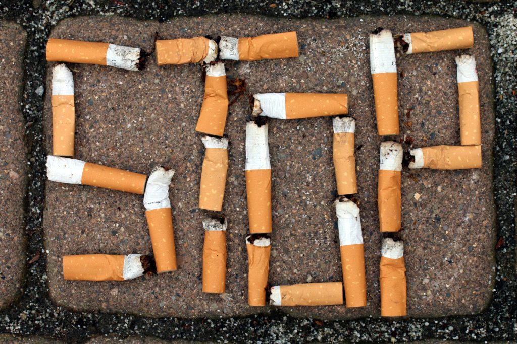 Wort "Stop" aus Zigarettenstummeln auf Pflaster