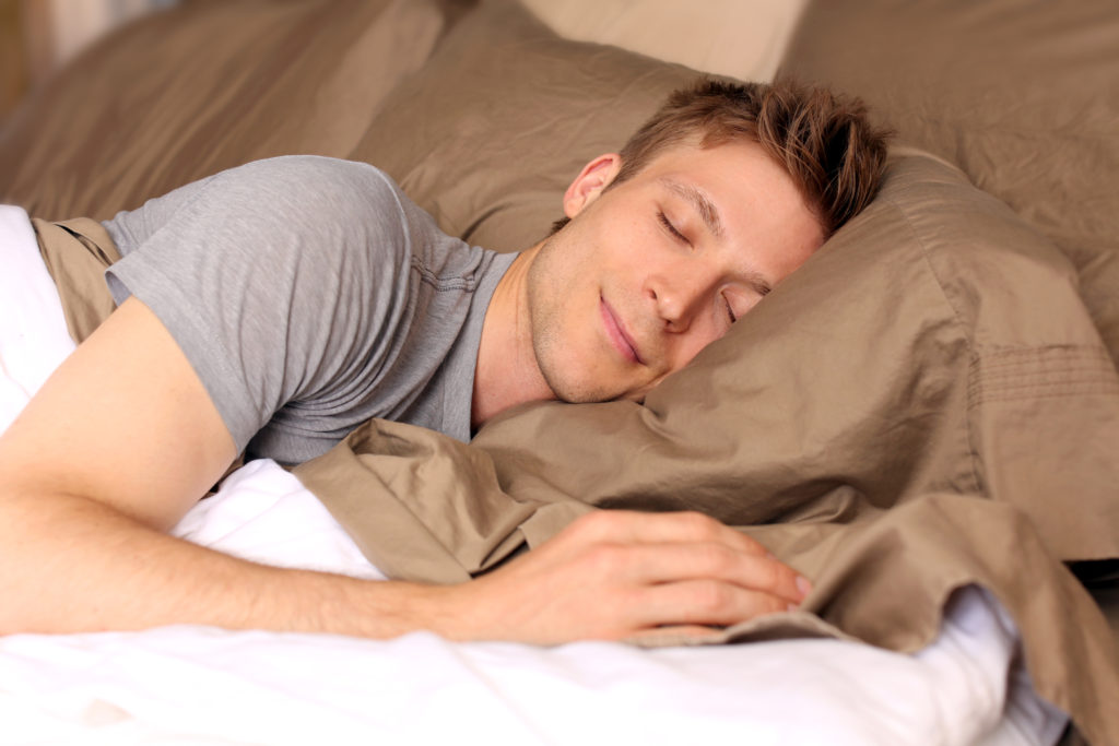 Young man comfortably sleeping in his bed