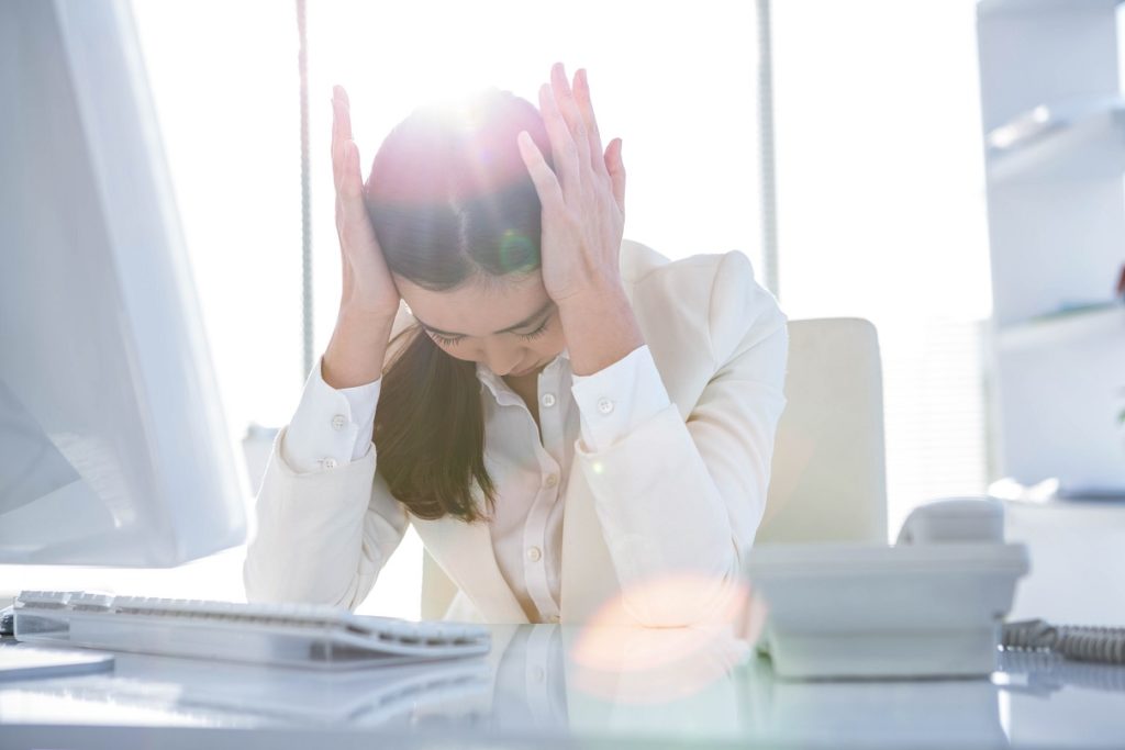 Frau im Büro hat Kopfschmerzen