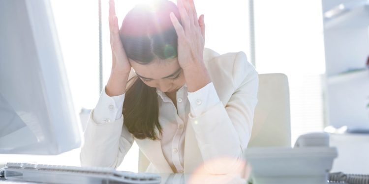 Frau im Büro hat Kopfschmerzen