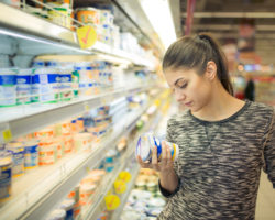 Frau liest sich im Supermarkt die Produktbeschreibung durch