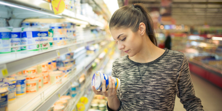 Frau liest sich im Supermarkt die Produktbeschreibung durch