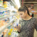 Frau liest sich im Supermarkt die Produktbeschreibung durch