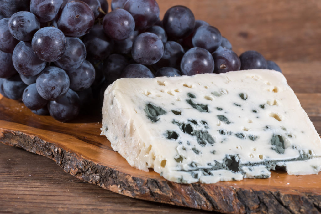 Blauschimmelkäse und blaue Trauben auf einem Brett