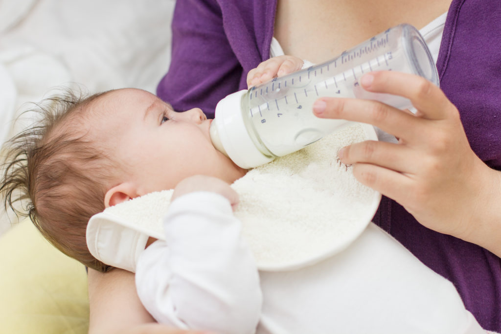 Frau füttert ihr Baby mit Milch aus der Nuckelflasche