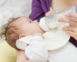 Frau füttert ihr Baby mit Milch aus der Nuckelflasche