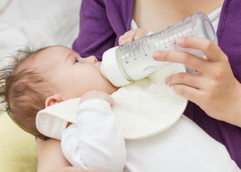 Frau füttert ihr Baby mit Milch aus der Nuckelflasche