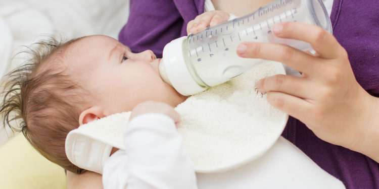 Frau füttert ihr Baby mit Milch aus der Nuckelflasche
