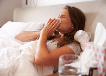 Frau liegt mit Erkältung im Bett