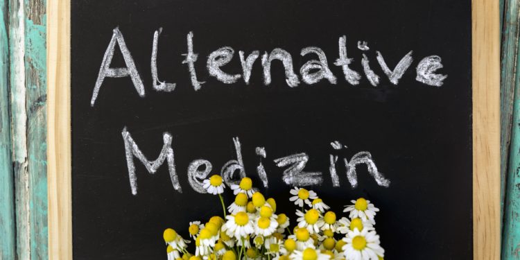 Ein Strauß Margeriten vor einer Tafel mit der Aufschrift: Alternative Medizin