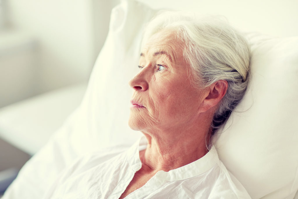 medicine, age, health care and people concept - senior woman patient lying in bed at hospital ward