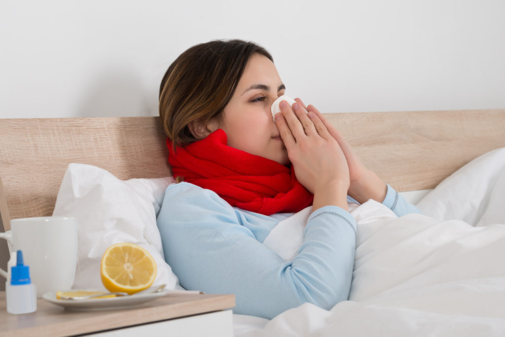 Frau krank im Bett mit Taschentuch