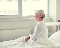 Ältere Frau sitzt auf einem Bett im Krankenhaus