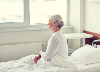 Ältere Frau sitzt auf einem Bett im Krankenhaus