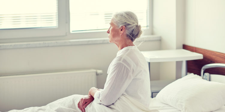 Ältere Frau sitzt auf einem Bett im Krankenhaus