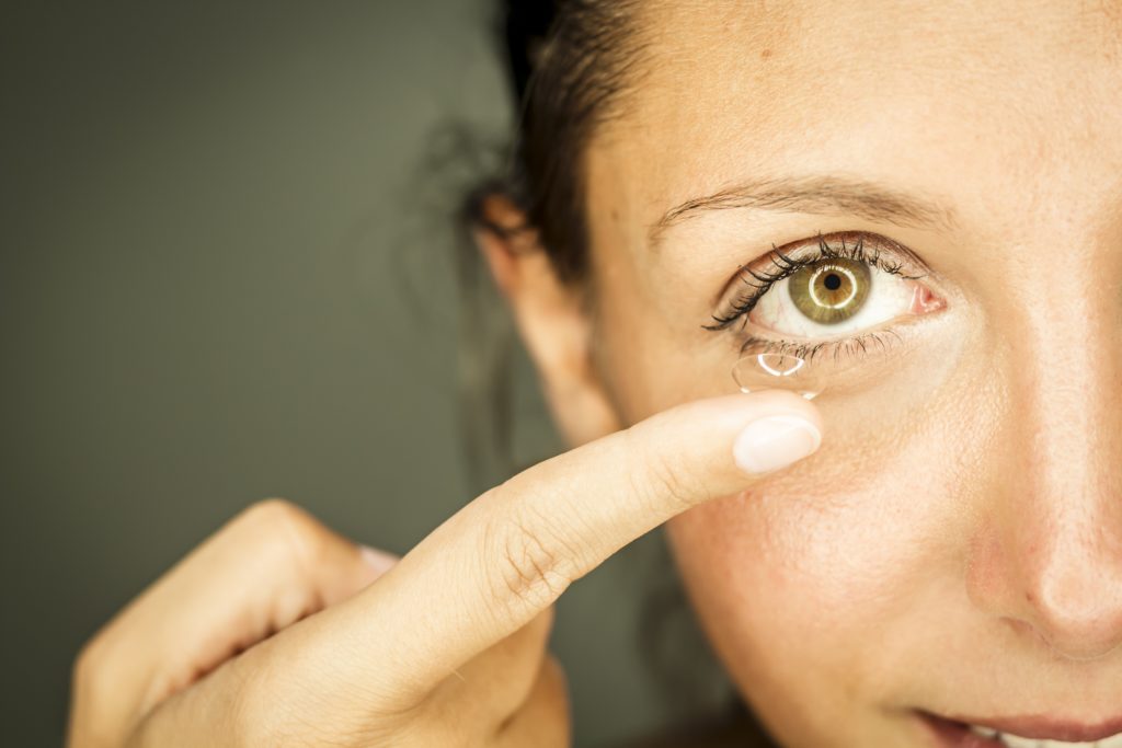 Frau entfernt Kontaktlinse aus dem Auge