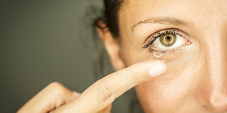 Frau entfernt Kontaktlinse aus dem Auge