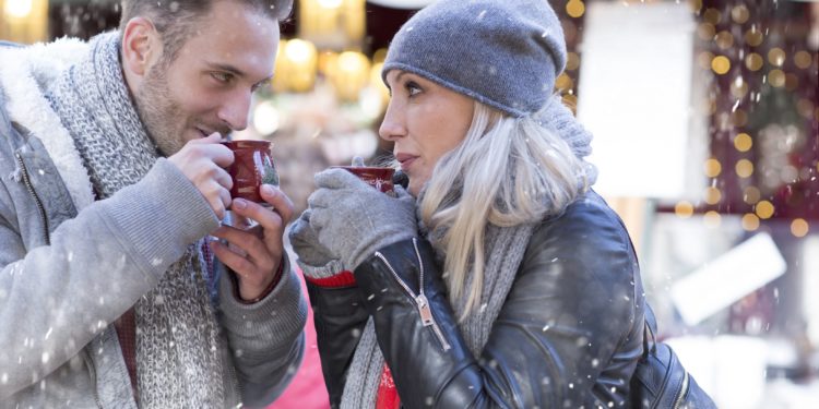 Ein Mann und eine Frau stehen im Schnee und trinken Glühwein.