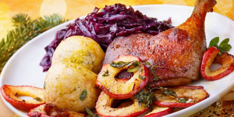 Ein üppiges Weihnachtsmahl mit einer Gänsekeule, Rotkohl und Klößen.